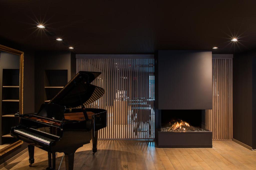 a black room with a piano and a fireplace at Le Florentin in Florenville