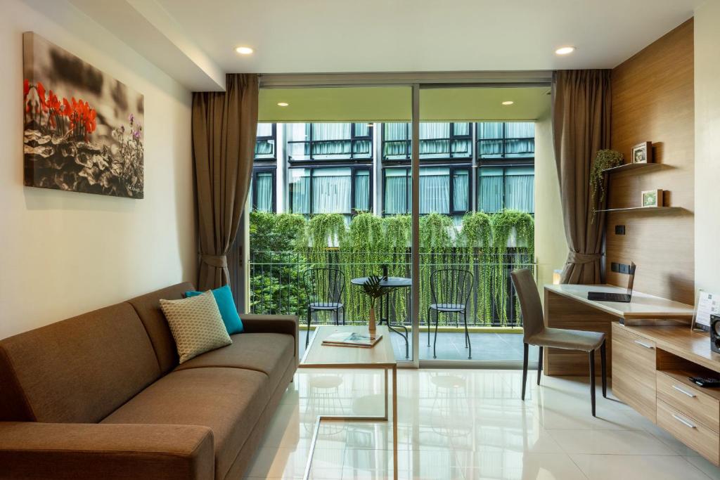 A bright living room opening onto a small balcony with a city-facing outlook.