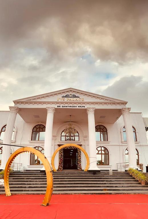 a white building with a red carpet and a large entrance at Sanctuary by JVS Palace in Hindupur