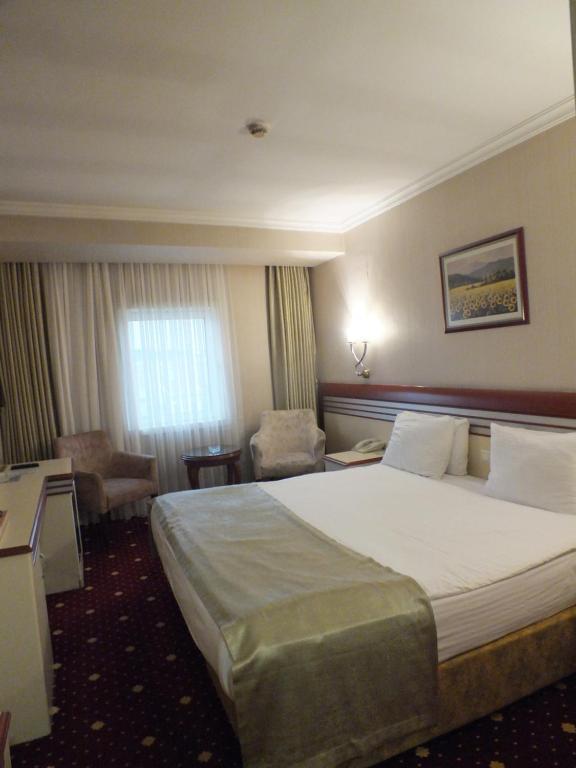 a hotel room with a large bed and a chair at Akar International Hotel in Ankara