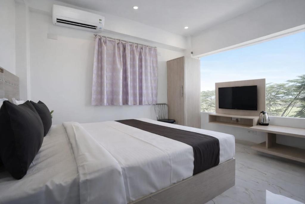 a white bedroom with a bed and a television at Hotel Shubh Bodhi in Bodh Gaya