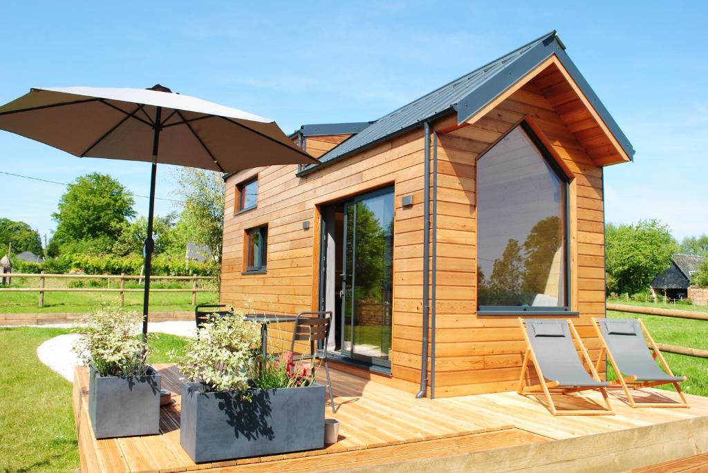 a tiny house with two chairs and an umbrella at Tiny House - La P'tite Georgette in Canouville