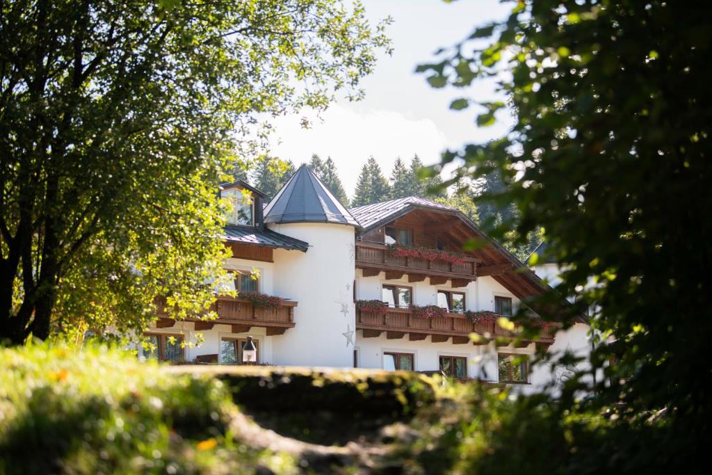 a large white building with balconies and trees at Hotel ZUM STERNENHOF in Kössen