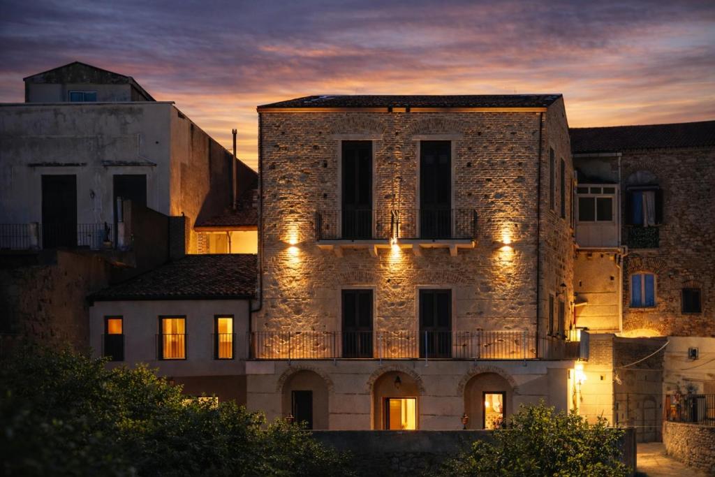 an old stone building with lights on it at dusk at La Filanda sul mare in Roccalumera