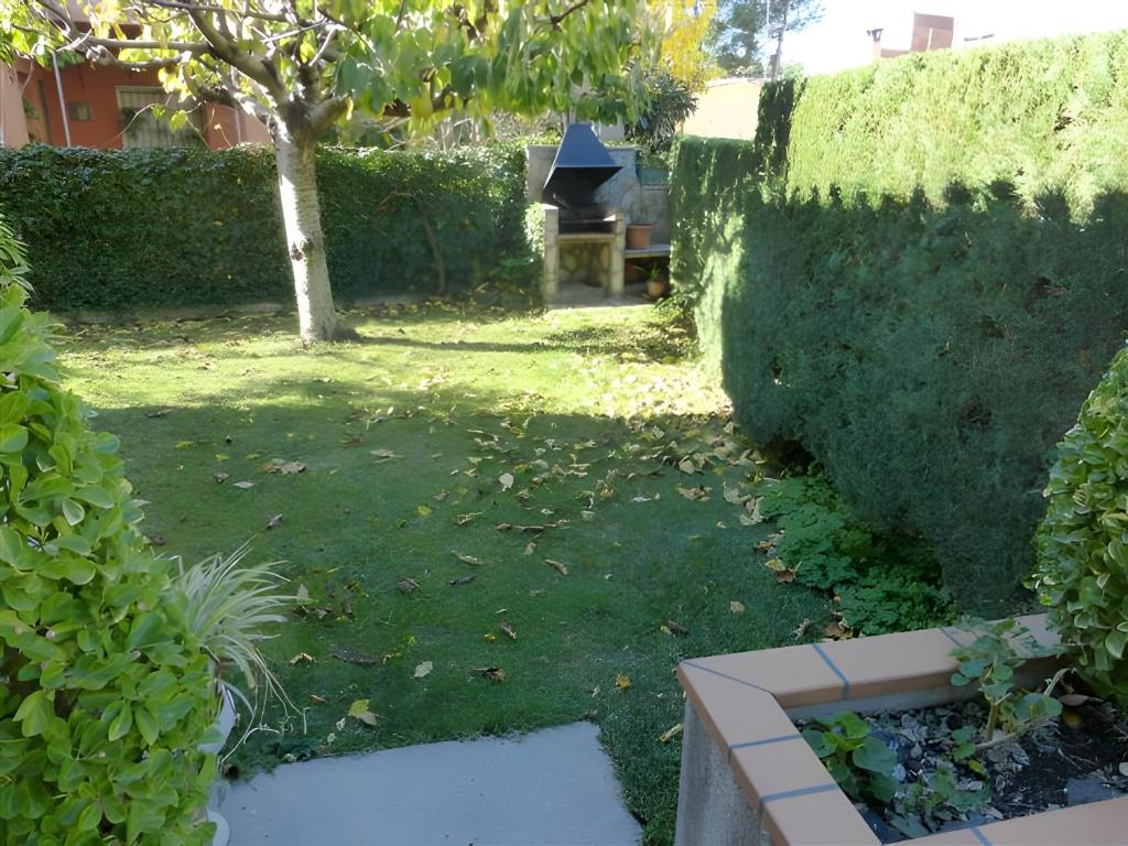 a garden with a hedge and a bench and a tree at Villa Rocamar in L'Escala