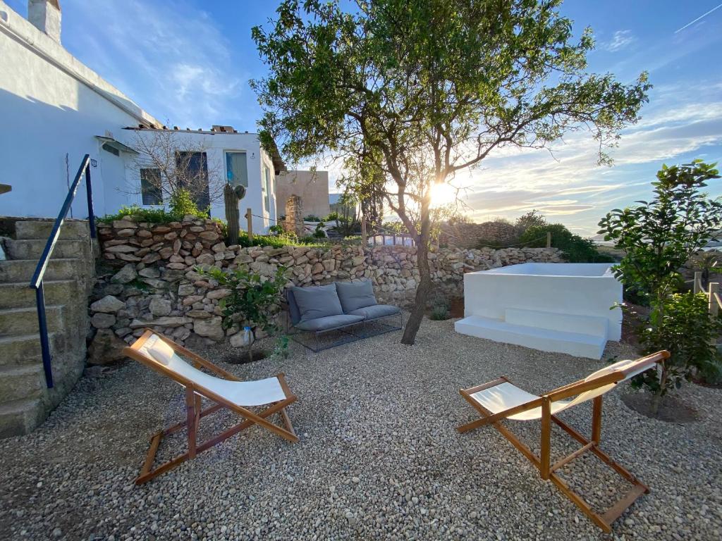 a patio with two chairs and a couch and a stone wall at Cortijo La Risca in Almería