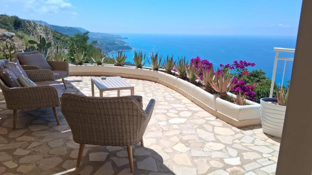 a patio with chairs and a table and the ocean at Villa Bella Vista in Zambrone