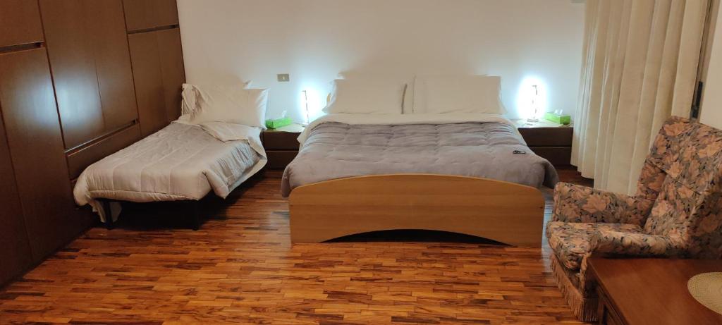 a hotel room with two beds and a chair at Oleggio apartment in Oleggio