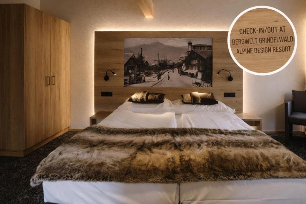 a bedroom with a large bed with a poster on the wall at Hotel PINTE in Grindelwald