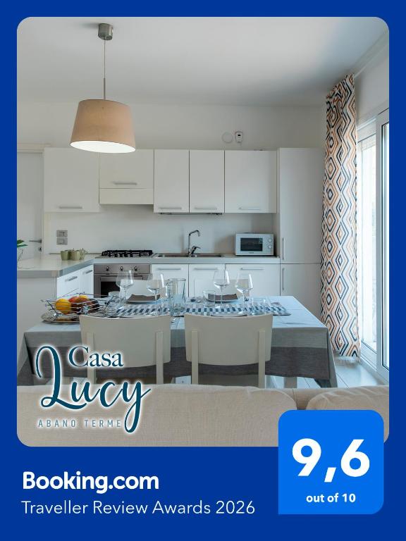 a kitchen with white cabinets and a table with chairs at Casa Lucy in Abano Terme