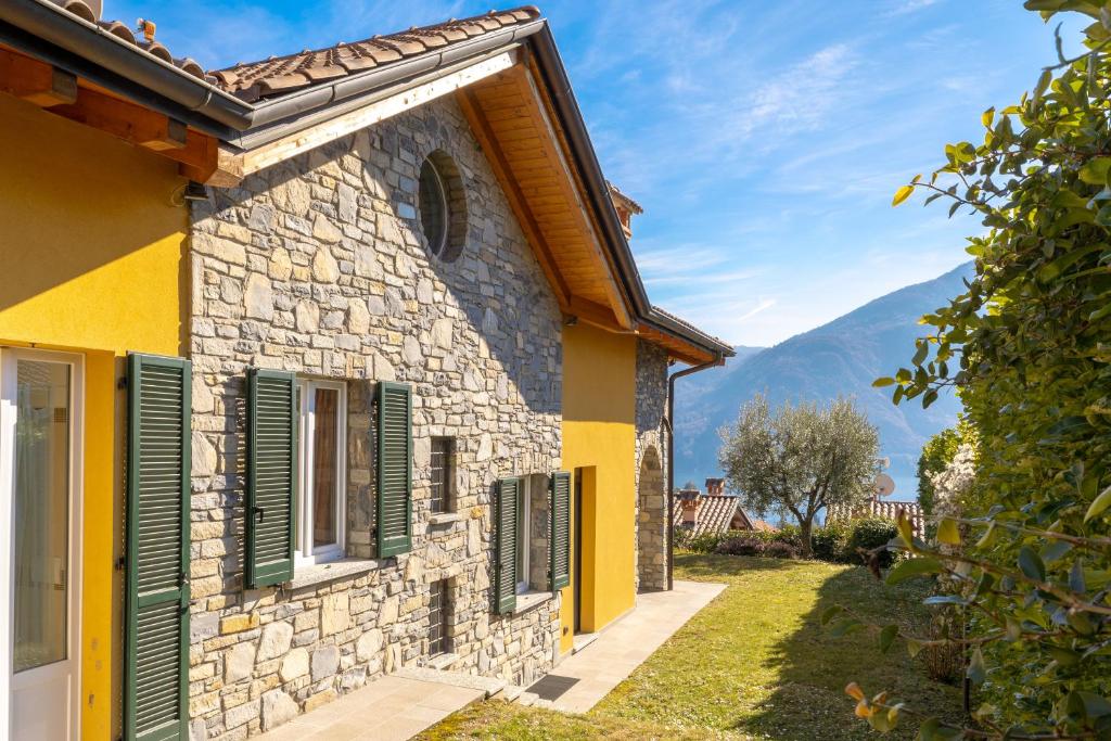 a stone house with green shutters on a building at Apartment Maya - Tremezzina in Tremezzo