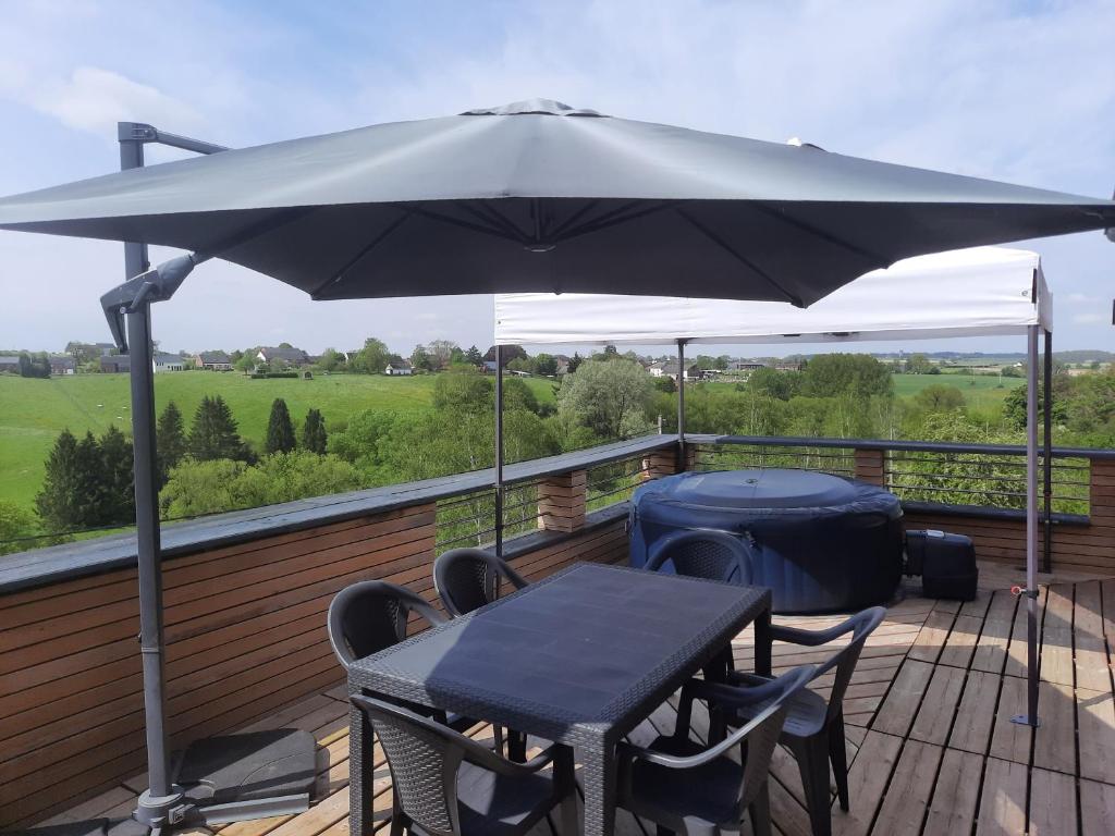 a table and chairs under an umbrella on a deck at Appartement Terrasse Jacuzzi du Pont Alsort 2-1 in Froid-Chapelle