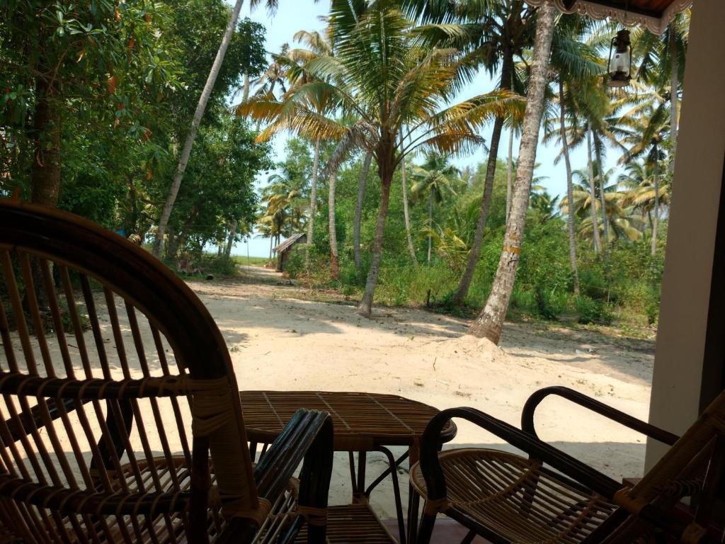 a porch with a table and chairs and palm trees at Marari Das Beach Villa in Mararikulam