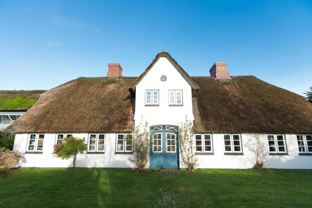 a large white house with a thatched roof at Hansen Hof 1 in Tinnum