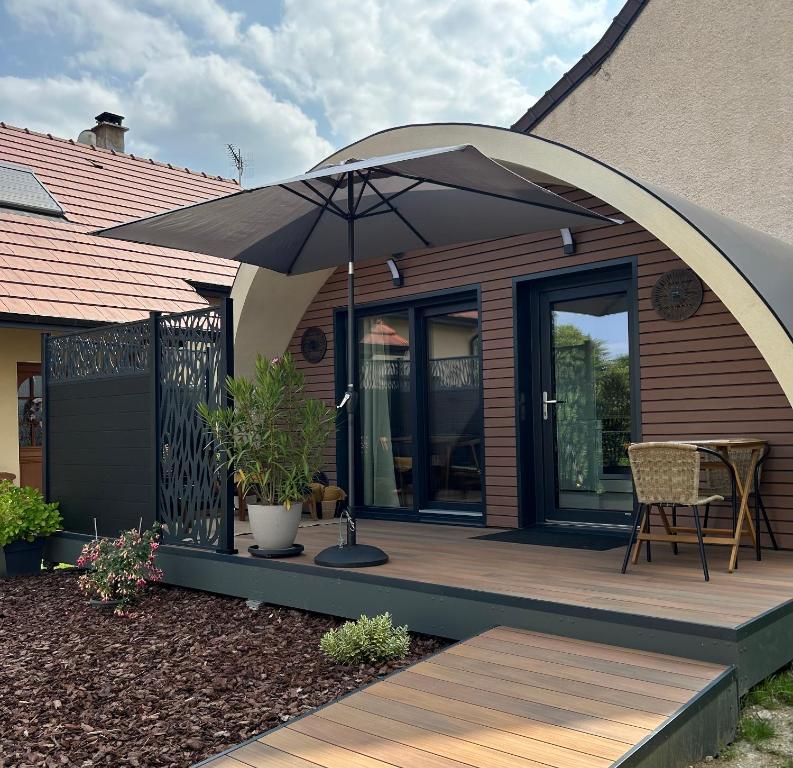 a wooden deck with an umbrella on a house at Ecolodge "Les Treilles Monet" Gîte insolite en Champagne à proximité d'Epernay in CumiÃ¨res