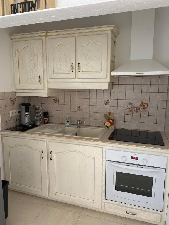 a kitchen with white cabinets and a sink at Petite maison de village in Ancerville