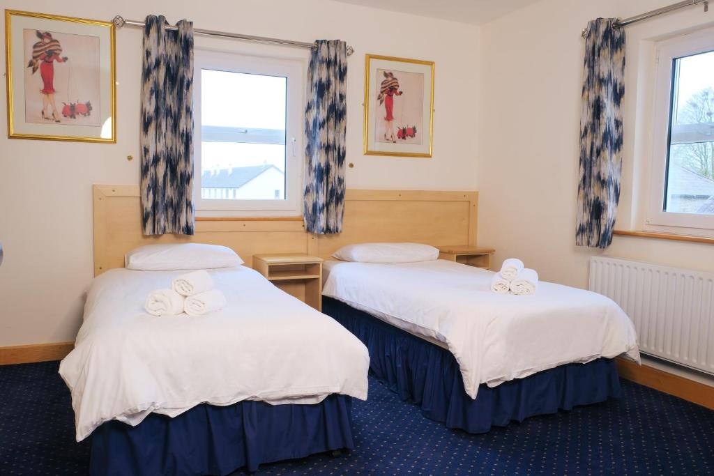 zwei Betten in einem Zimmer mit zwei Fenstern in der Unterkunft Feerick's Hotel in Rathowen