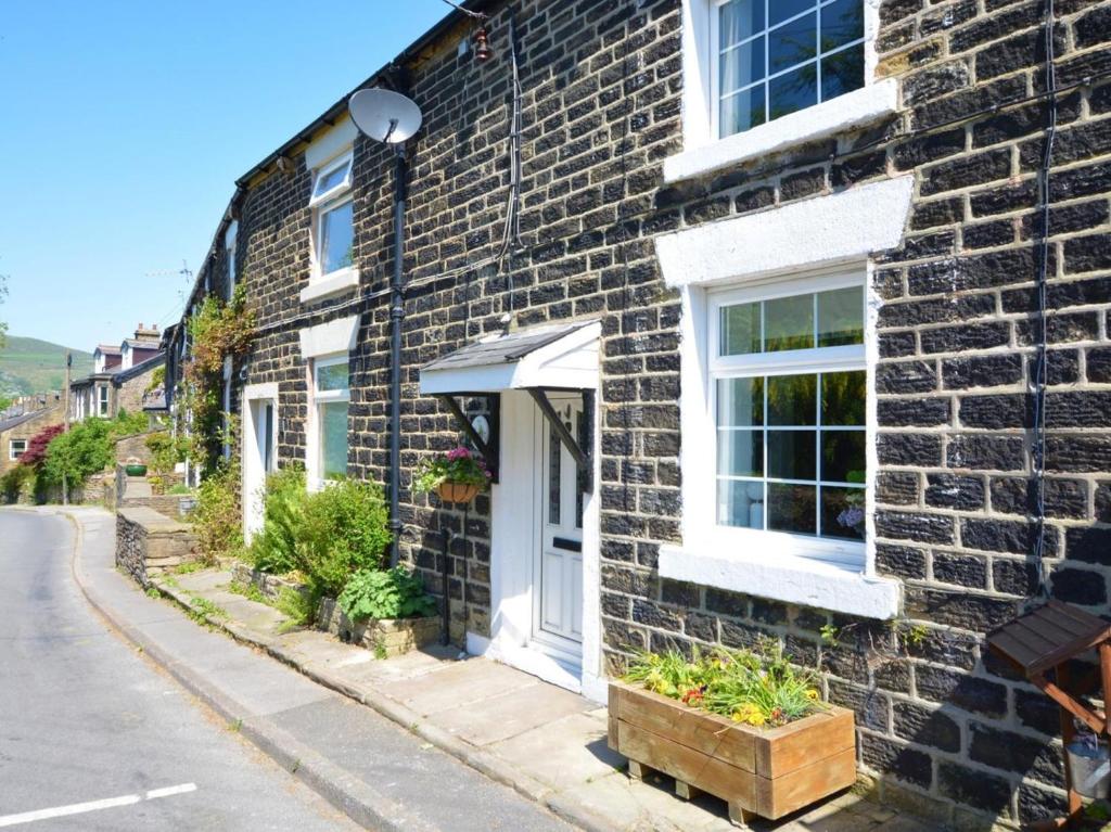 a brick house with a white door on a street at 2 Bed in High Peak oc-57871 in Hayfield