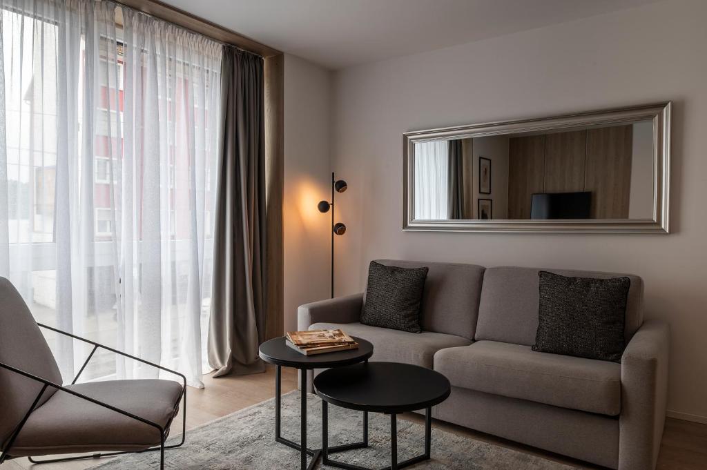 a living room with a couch and a table and a mirror at Aparthotel Cosy in Stuttgart