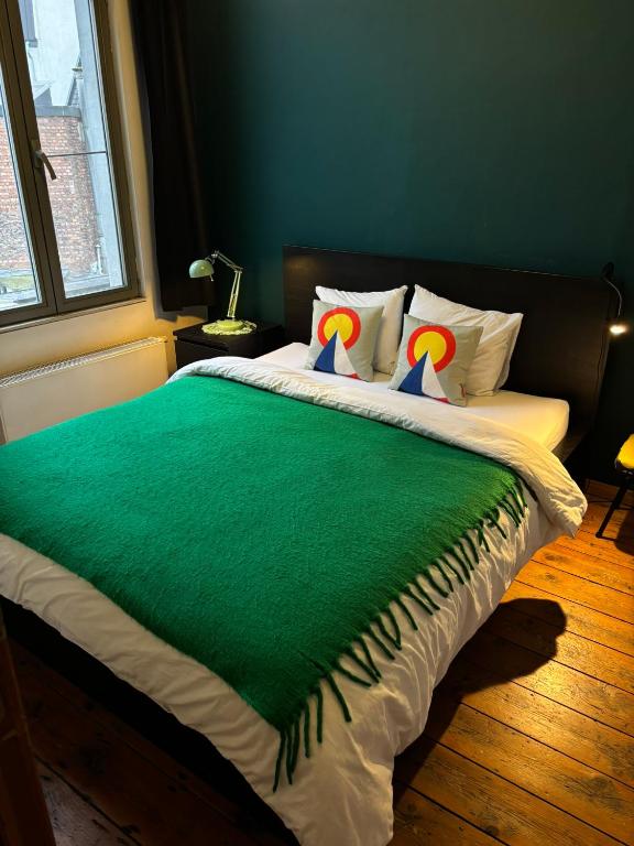 a bedroom with a bed with a green blanket on it at Vintage Lovers Antwerp in Antwerp