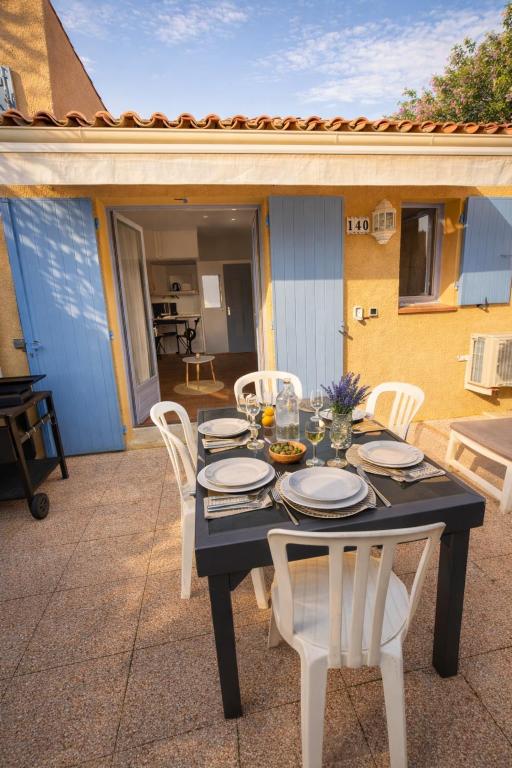 a black table and white chairs on a patio at Mazet avec piscine collective in Le Lavandou