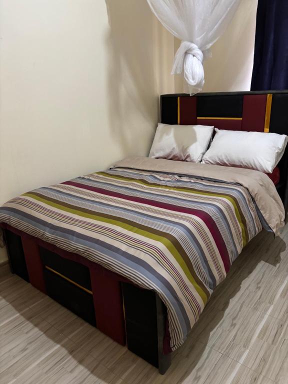 a bed with a colorful striped blanket on it at Next Level in Gulu