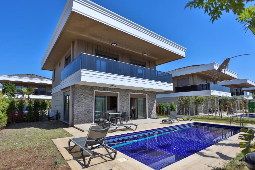 a villa with a swimming pool and a house at Nirvana Belek Villas Manolya in Belek