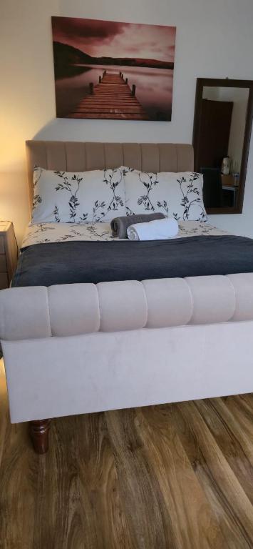 a bedroom with a white bed with a wooden floor at Apple House Wembley in Barnet