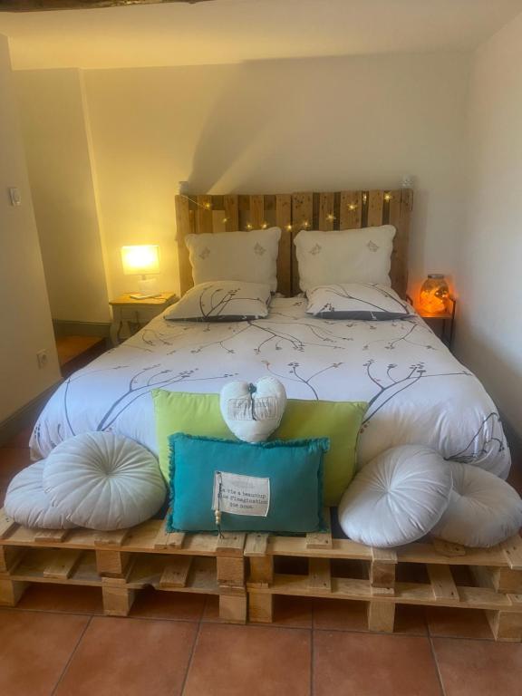 a bedroom with a bed with pillows on a wooden bench at Chambre Le Colibri in Lezoux