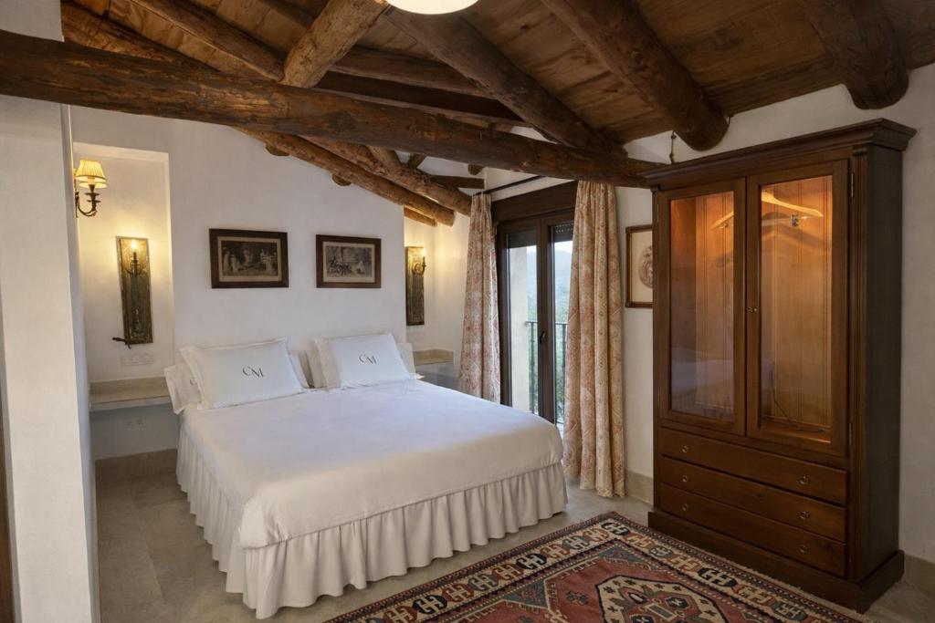 a bedroom with a white bed and a wooden ceiling at Casa Malinalco Hotel Boutique & Restaurante in Sotosalbos