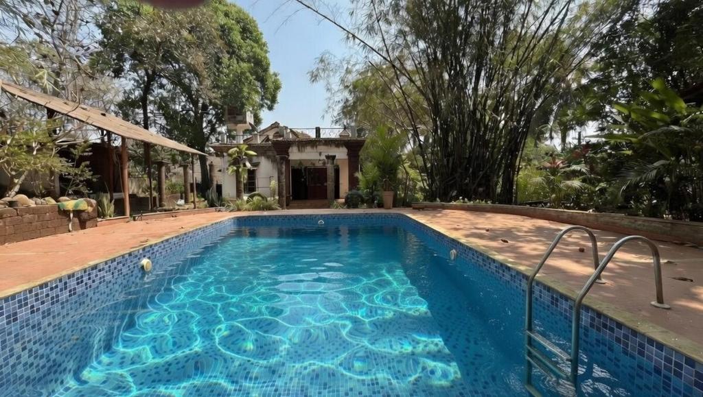 a swimming pool in front of a house at Abraham's 4 BHK villa, By Gonserv in Jāmb