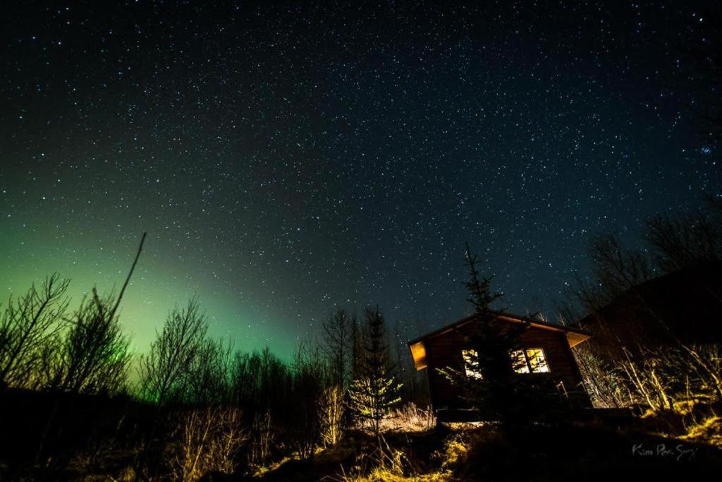 a starry night with a cabin in a field at Skard Cottages in Fludir