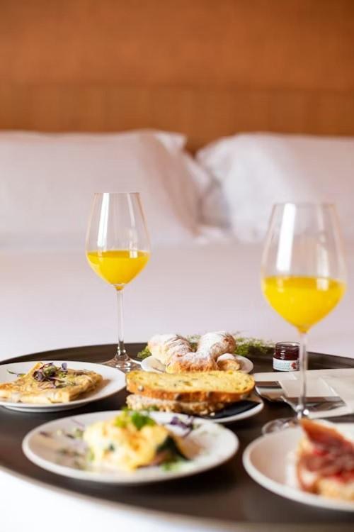 a table with plates of food and two glasses of wine at Latitudo Suites Uganda in Kajansi