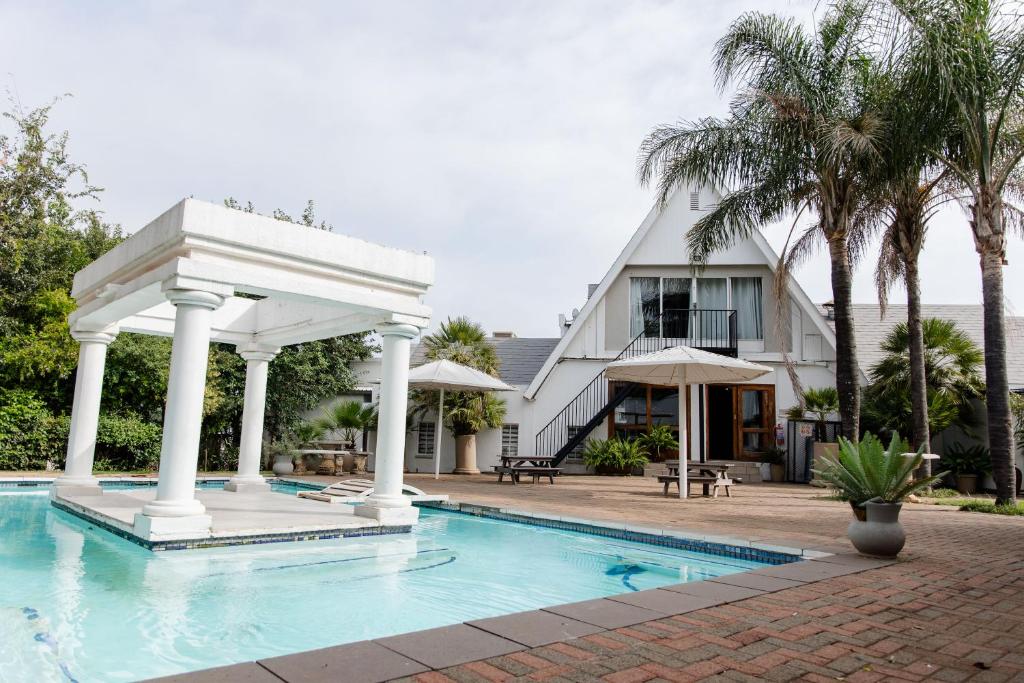 a swimming pool with a gazebo next to a house at St Andrews exclusive guesthouse in Klerksdorp