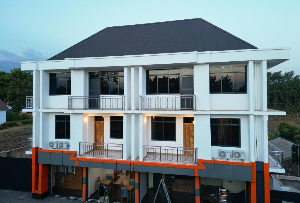 a white building with a black roof at Kiliscape Hotel Moshi in Uru