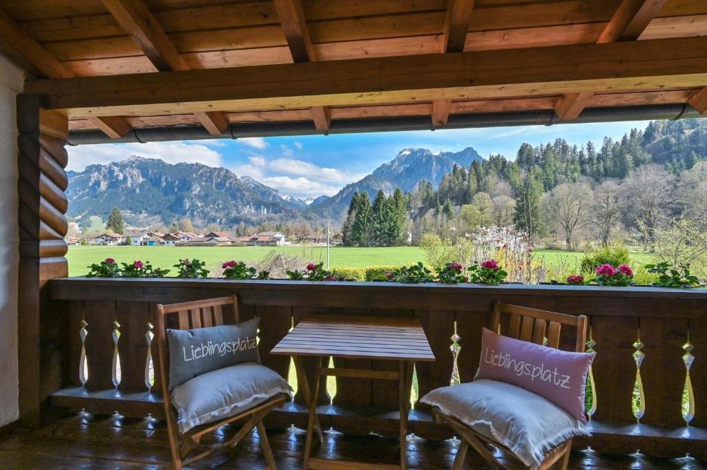 a porch with two chairs and a table and a view at Haus Bella in Schwangau