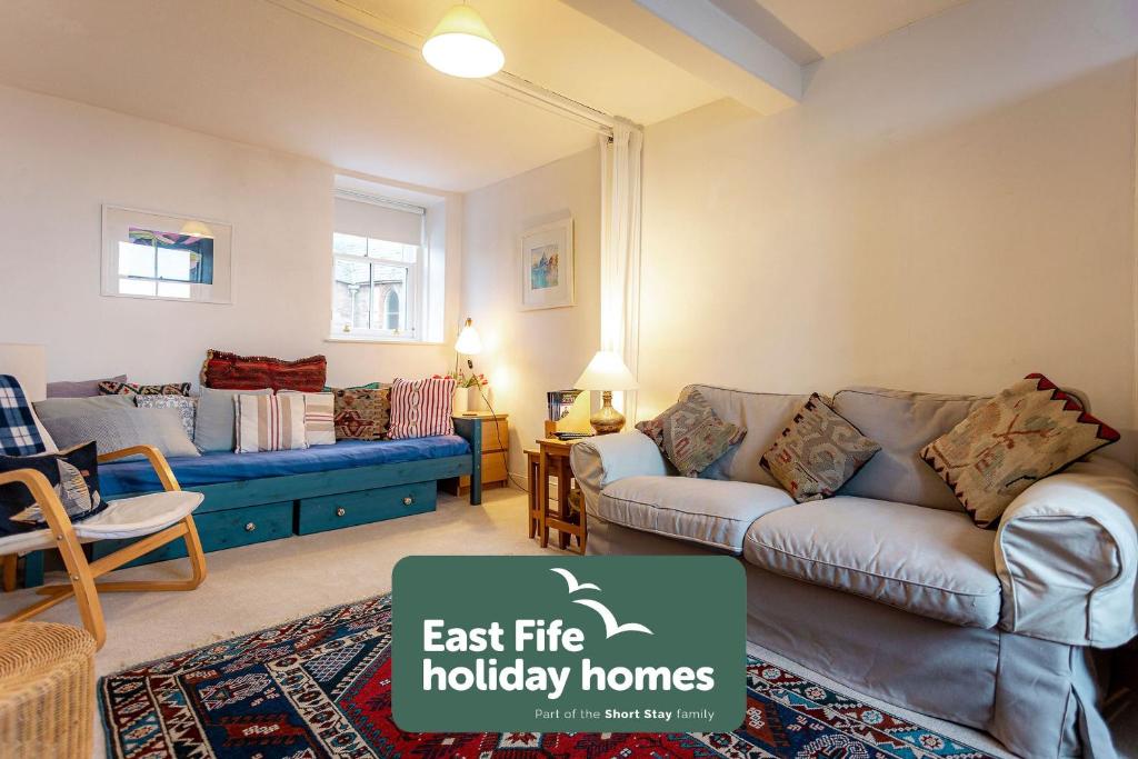 a living room with a couch and a table at Harbour View Apartment - Crail in Crail