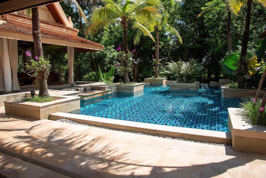 a swimming pool in a yard with palm trees at Baan Na Villa in Satuk