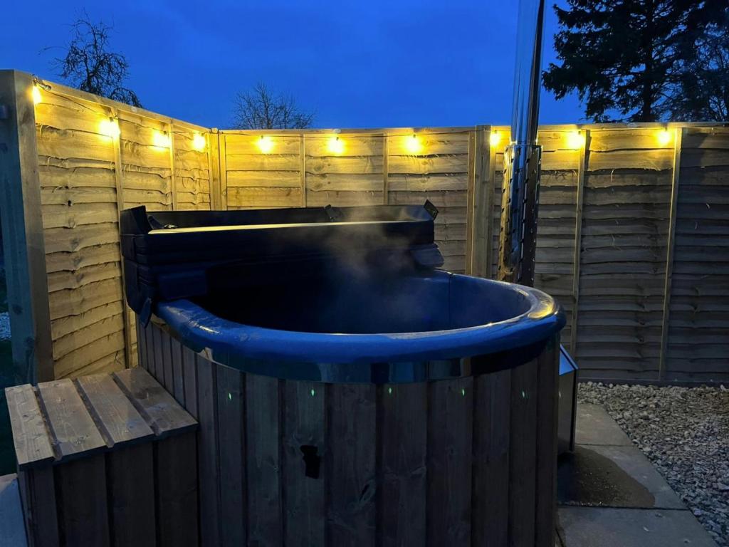 a hot tub in a backyard with lights on a fence at Finest Retreats - The Flower Hut in Charlton