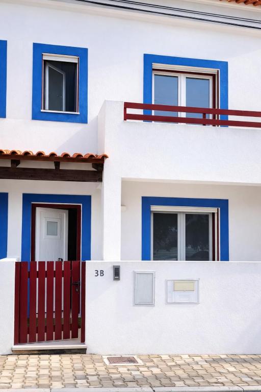 a white and blue house with a red gate at Casa de Melides in Melides