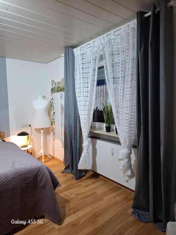 a bedroom with a bed and a window with curtains at Ferienwohnung Seeblick in Langweiler