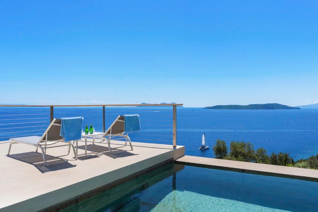 two chairs and a swimming pool with a view of the water at VILLA ODISSOS - Private Paradise with 2 infinity pools & Sea access in Sivota
