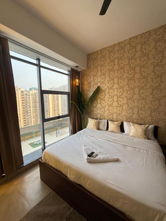 a bedroom with a large bed with a large window at Fifth Heaven Studio at Spectrum Mall in Noida