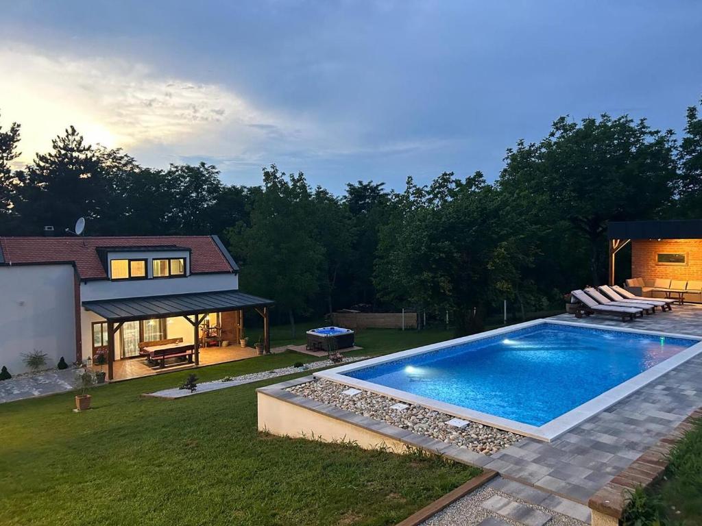 a backyard with a swimming pool and a house at Villa BELEVITA odmor u prirodi sa grijanim bazenom in Čepelovac