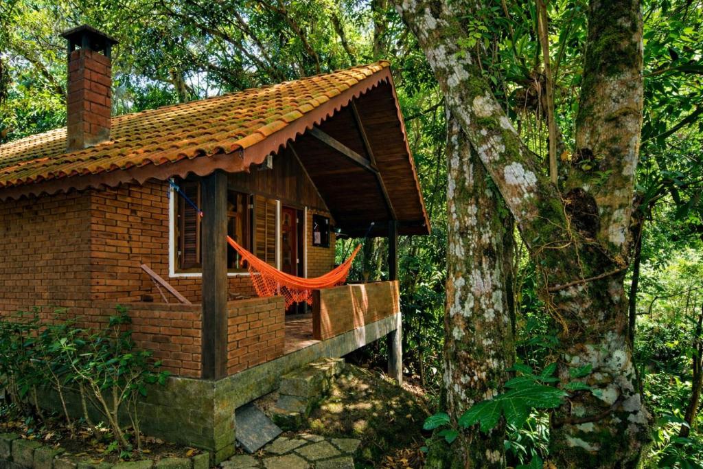 a small brick house with a red hammock in front at Pousada do Rio Maua in Visconde De Maua