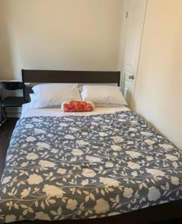 a bed in a bedroom with a flower patterned blanket at Comfortable Room with Free Parking in Brampton