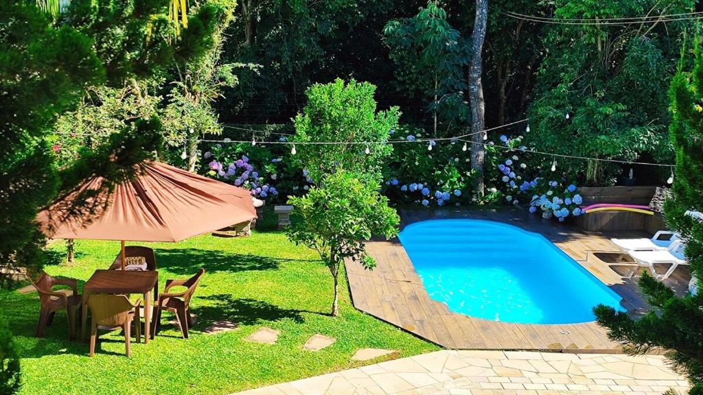 a swimming pool in a yard with chairs and an umbrella at Casaloft994 in Bento Gonçalves