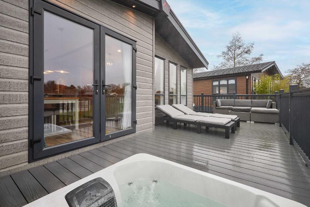 a bath tub sitting on a deck next to a house at Sandy Lane 18 - Lodge with Hot Tub in Allerthorpe