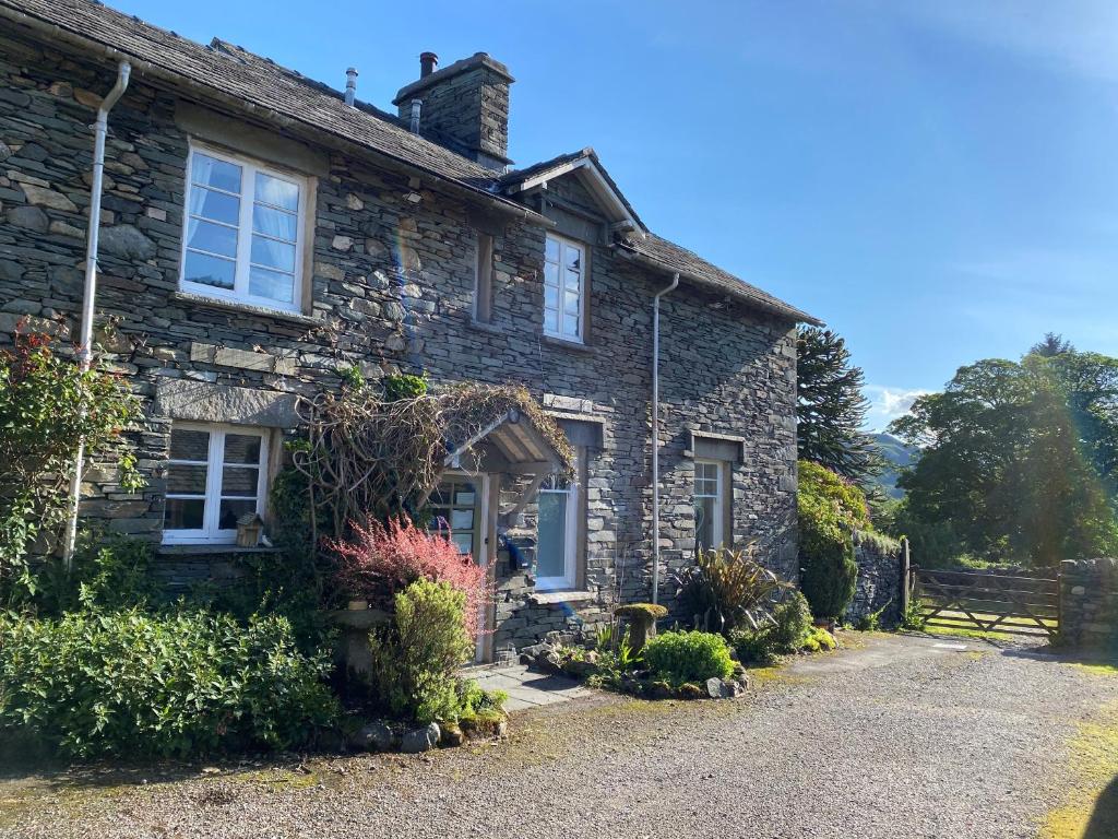 an old stone house with flowers in front of it at Elterwater Park self catering in Ambleside