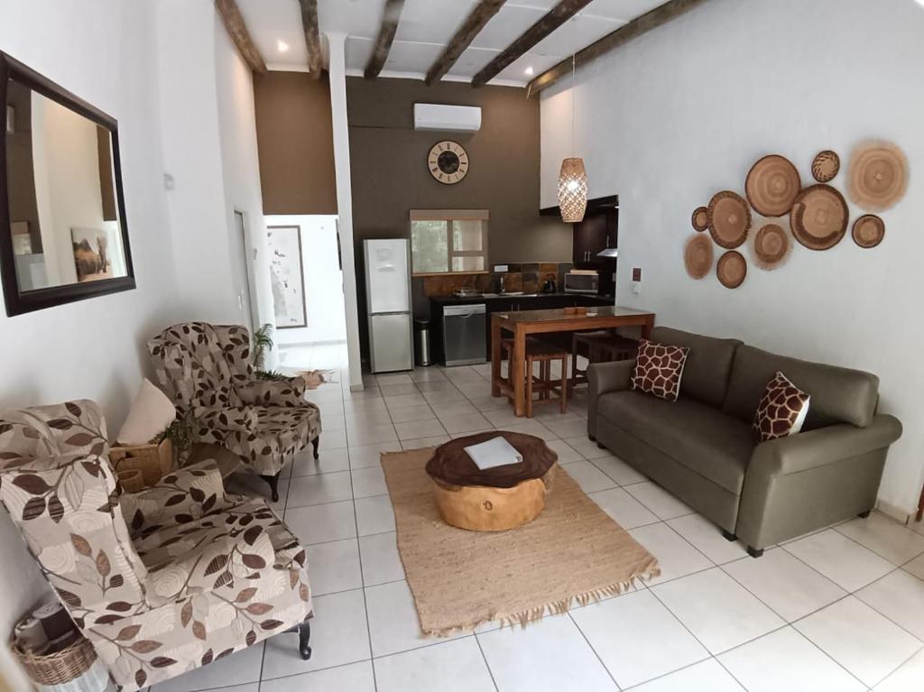 a living room with a couch and chairs and a table at Marloth Cottage in Marloth Park